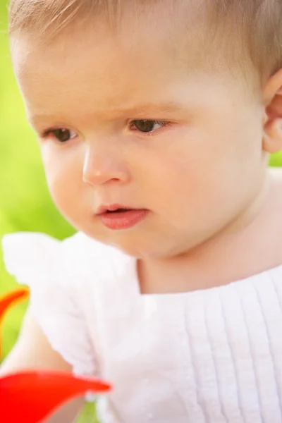 Yel değirmeni holding alanında oturup yaz elbise kız bebek — Stok fotoğraf