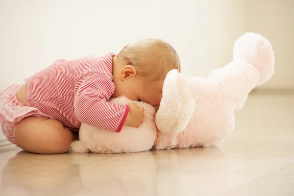 Bebê menina abraçando ursinho de pelúcia rosa em casa — Fotografia de Stock