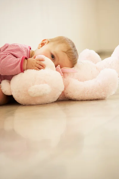 Bebê menina abraçando ursinho de pelúcia rosa em casa — Fotografia de Stock