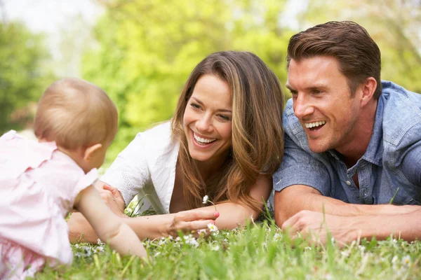 Ouders met babymeisje zit op gebied van zomerbloemen — Stockfoto