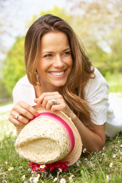 女性麦わら帽子と夏の花のフィールドに横になっています。 — ストック写真