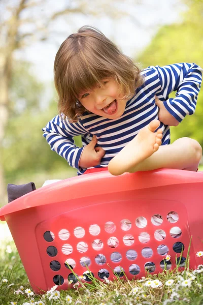 Menino jovem sentado na cesta da lavanderia — Fotografia de Stock