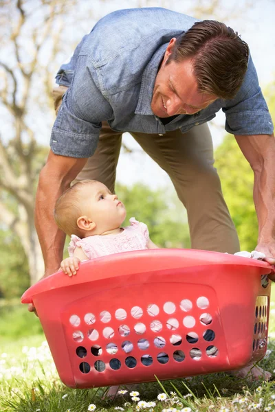 Far bär baby flicka sitter i tvättkorgen — Stockfoto