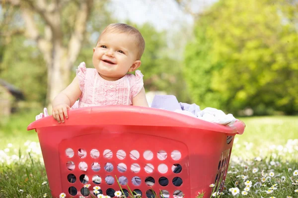 Baby flicka i sommarklänning sitter i tvättkorg — Stockfoto