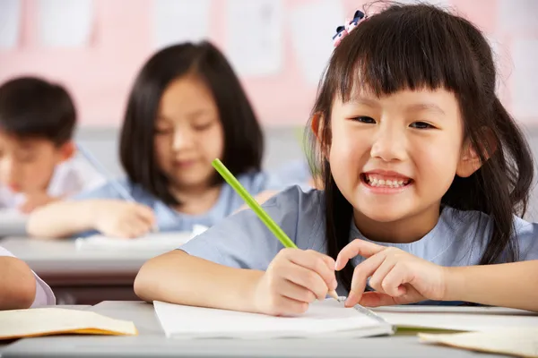 Groep studenten werken bij bureaus in chinese school klas — Stockfoto