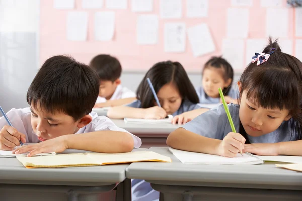 Groep studenten werken bij bureaus in chinese school klas — Stockfoto