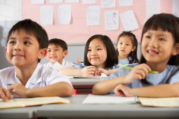 Grupo de estudiantes que trabajan en escritorios en el aula de la escuela china — Foto de Stock