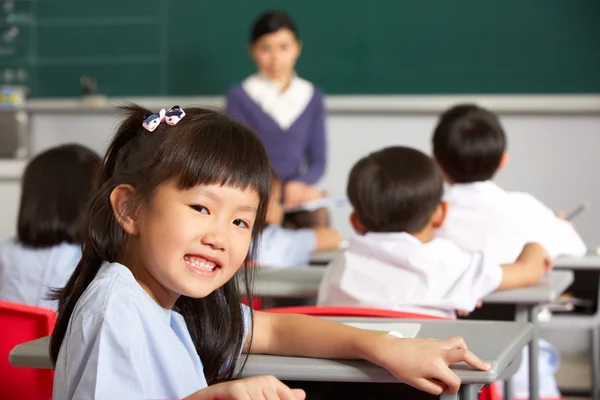 Porträt einer Schülerin, die in einer chinesischen Schulklasse am Schreibtisch arbeitet — Stockfoto