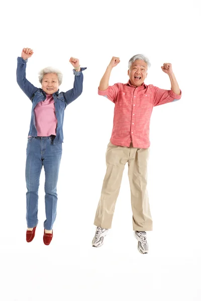 Studio Shot of Chinese Senior Couple Jumping In Air — стоковое фото