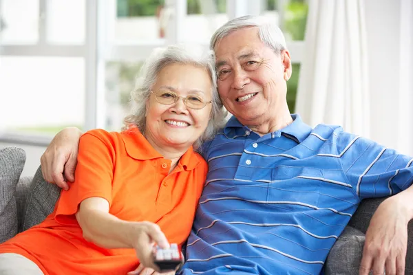 Casal chinês sênior assistindo TV no sofá em casa — Fotografia de Stock