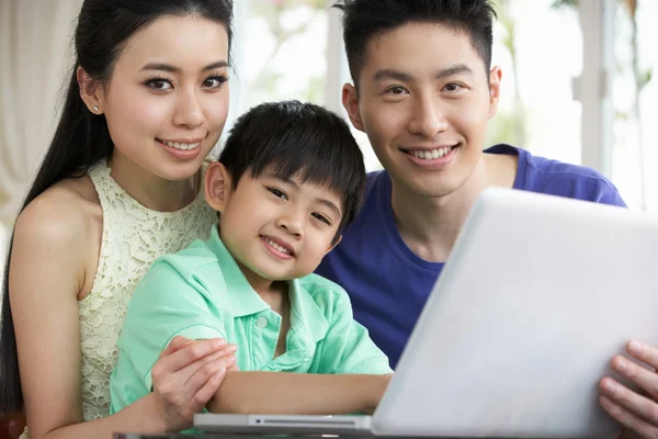 Família chinesa sentada na mesa usando laptop em casa — Fotografia de Stock