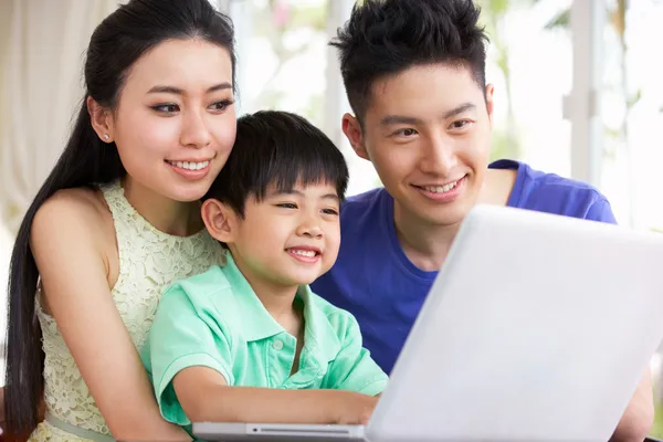 Família chinesa sentada na mesa usando laptop em casa — Fotografia de Stock