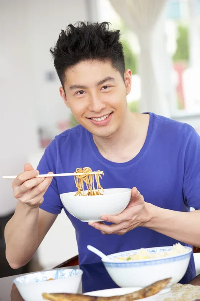 Jovem chinês sentado em casa comendo refeição — Fotografia de Stock