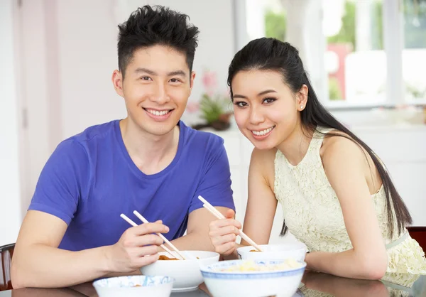 Giovane coppia cinese seduta a casa mangiare pasto — Foto Stock