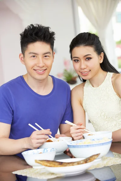 Joven pareja china sentada en casa comiendo comida — Foto de Stock