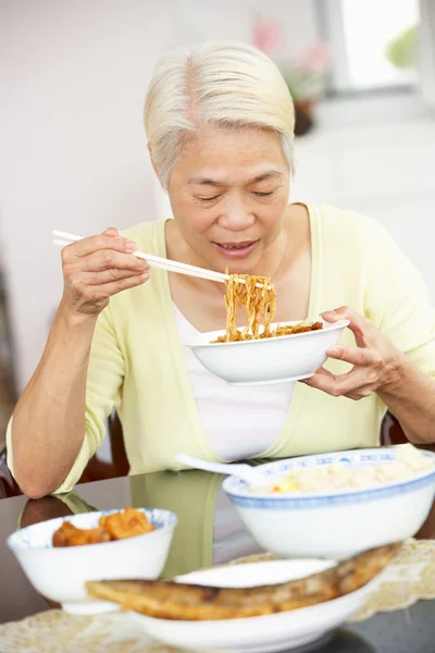 Senior mujer china sentada en casa comiendo comida — Foto de Stock