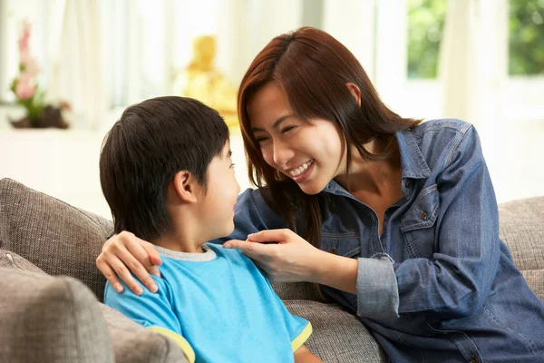 Madre e hijo chinos sentados en un sofá en casa juntos — Foto de Stock