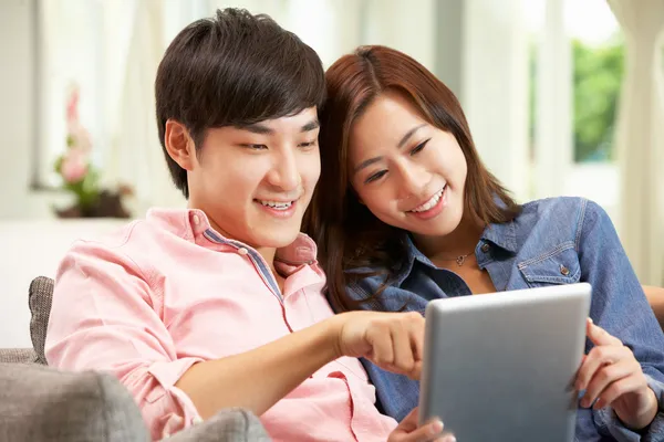 Joven pareja china usando tableta digital mientras se relaja en Sof —  Fotos de Stock