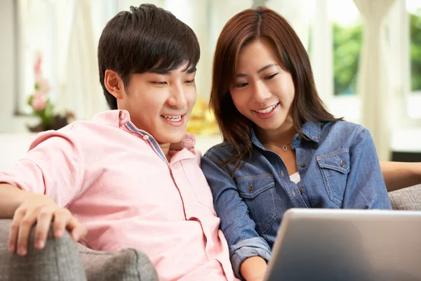 Casal chinês jovem usando laptop enquanto relaxa no sofá no Hom — Fotografia de Stock