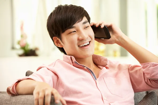Young Chinese Man Using Mobile Phone On Sofa At Home — Stock Photo, Image