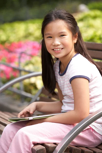 Retrato de chica china sentada en el banco del parque con Tabl digital — Foto de Stock