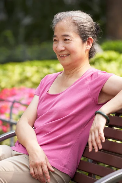 Senior chinês mulher relaxante no parque banco — Fotografia de Stock