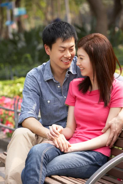 Jovem casal chinês relaxando no banco do parque juntos — Fotografia de Stock