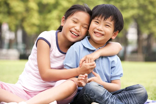 Porträt eines chinesischen Jungen und eines chinesischen Mädchens, die zusammen im Park sitzen — Stockfoto