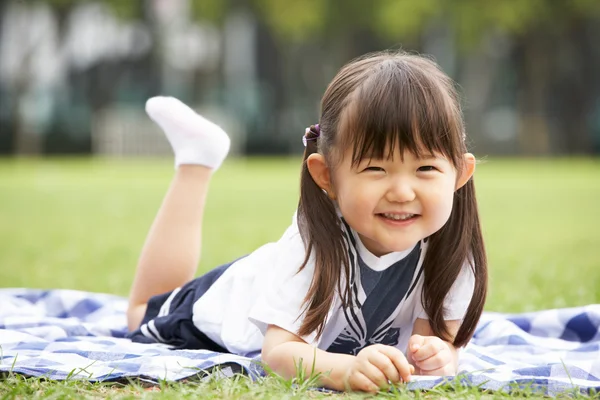 Jonge Chinees meisje liggend op deken in park — Stockfoto