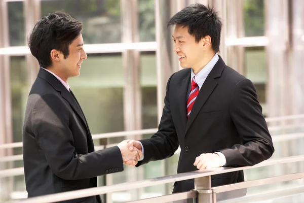Dois empresários chineses tremendo mãos fora do escritório — Fotografia de Stock
