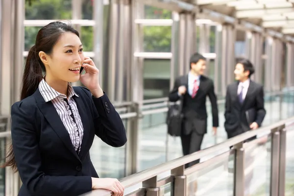 Čínská podnikatelka mimo kancelář na mobilním telefonu s collea — Stock fotografie