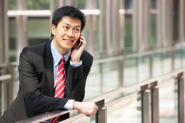 Retrato de empresário chinês fora do escritório no telefone móvel — Fotografia de Stock