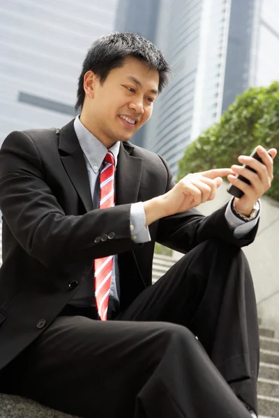 Chinês empresário discando no telefone móvel fora do escritório — Fotografia de Stock