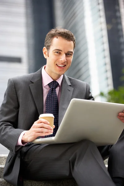 Zakenman die op laptop buiten kantoor met afhaalmaaltijden coffe werkt — Stockfoto
