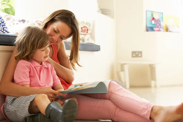 Mutter sitzt mit Sohn im Haus und liest Geschichte Stockbild