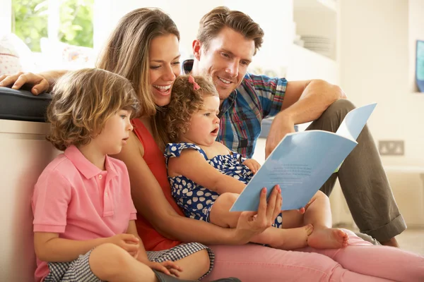 Eltern sitzen mit Kindern und lesen Geschichte lizenzfreie Stockbilder