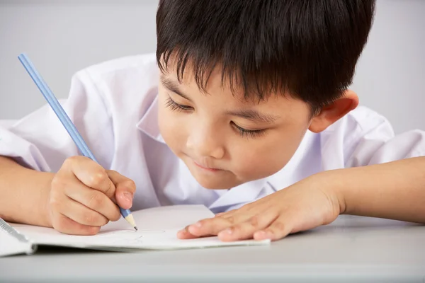 Mannelijke student werkt aan balie in chinese school klas Stockfoto