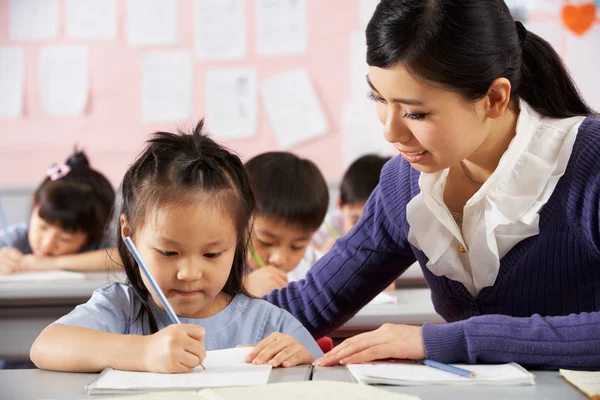 Çinli okul classr masasında çalışan öğrenci yardımcı öğretmen Telifsiz Stok Imajlar