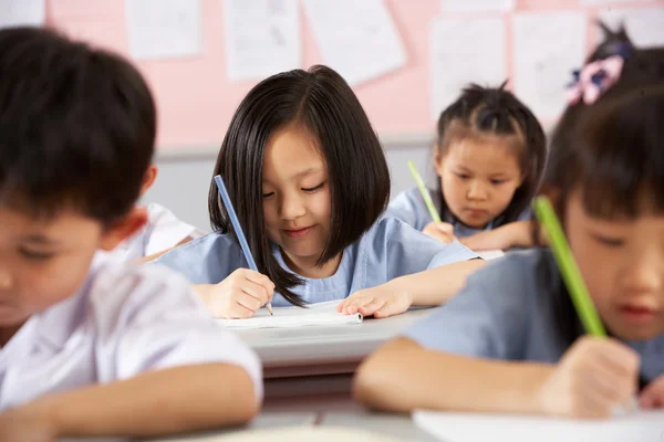 Groep studenten werken bij bureaus in chinese school klas Stockfoto