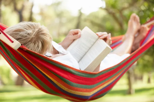 Seniorin entspannt sich in Hängematte mit Buch — Stockfoto