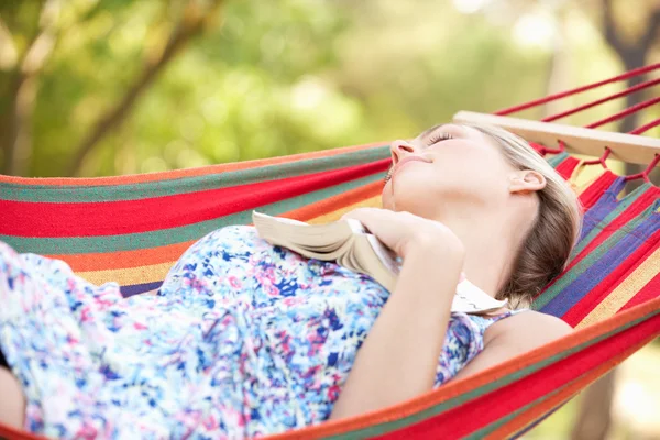 Mulher relaxante em rede com livro — Fotografia de Stock