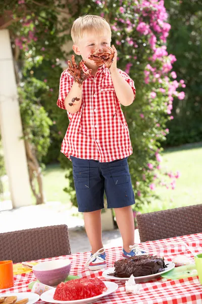 Jongen gelei en taart eten op buiten tea party — Stockfoto