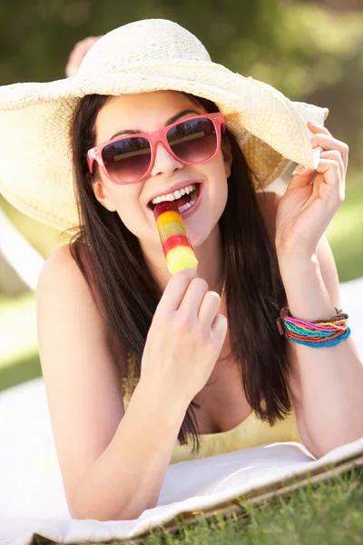 Mujer relajante en jardín comiendo hielo lolly — Foto de Stock