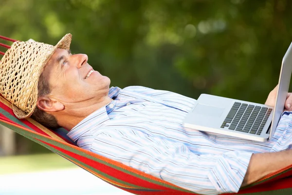 Senior Mann entspannt sich in Hängematte mit Laptop — Stockfoto