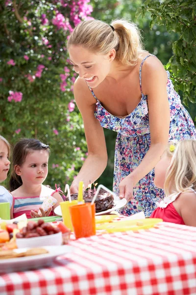 Madre che serve torta di compleanno al gruppo di bambini all'aperto — Foto Stock