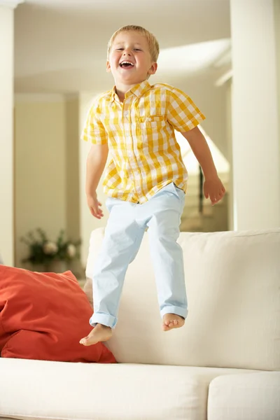 在家里的沙发上跳跃的年轻男孩 — 图库照片