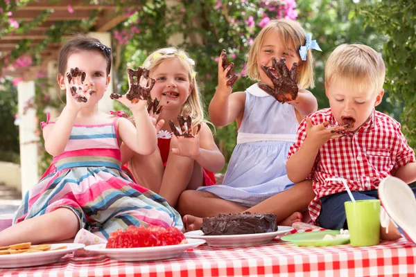 Grupo de crianças comendo geléia e bolo na festa de chá ao ar livre — Fotografia de Stock