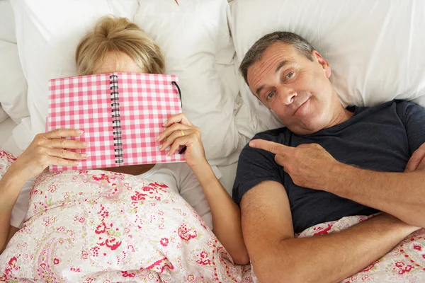 Entediado olhando o homem sênior deitado na cama ao lado da mulher sênior Readi — Fotografia de Stock