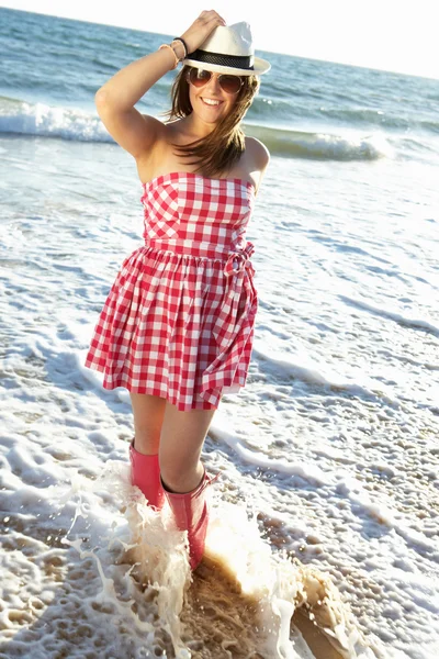 少女穿惠灵顿靴溅在海滩上的海洋 — 图库照片