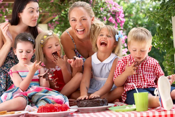 Niños y madres comiendo jalea y pastel en la fiesta de té al aire libre —  Fotos de Stock